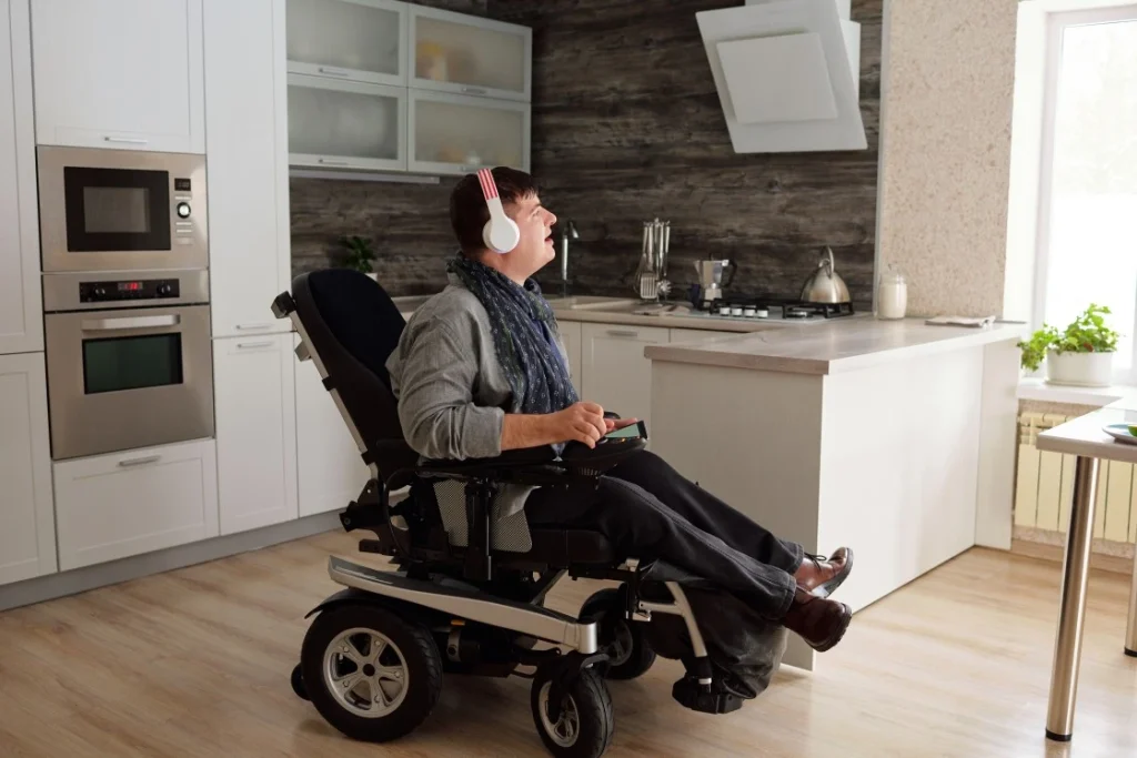 Disabled man in wheelchair in kitchen with headphones on