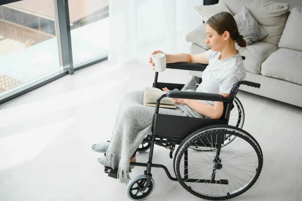 Disabled woman in wheelchair reading a book with a mug of tea